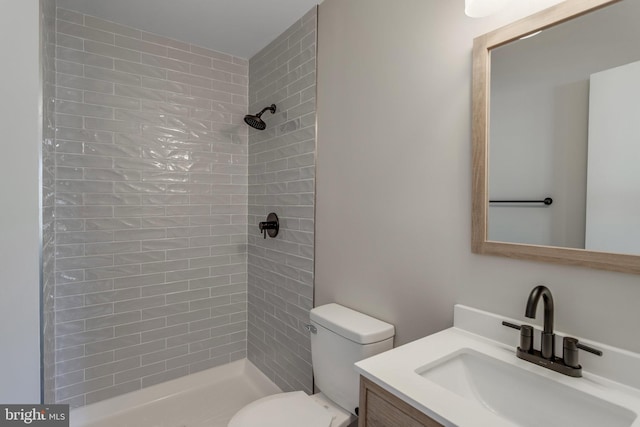 bathroom featuring vanity, toilet, and a tile shower