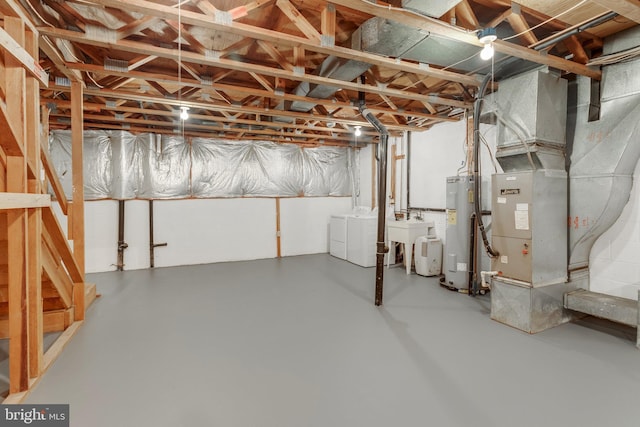 basement featuring heating unit, sink, electric water heater, and washer and dryer