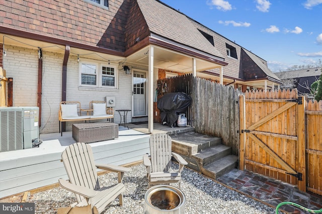 deck featuring area for grilling, central AC unit, fence, and a gate