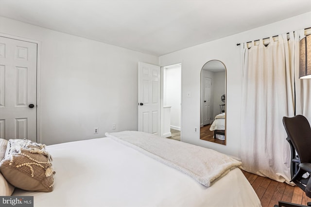 bedroom featuring arched walkways and dark wood-style flooring