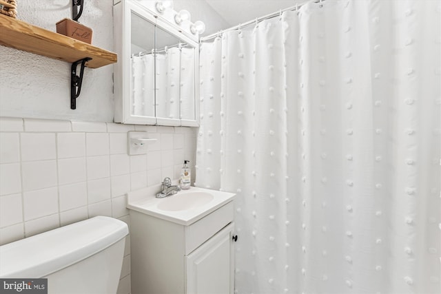 full bath with vanity, tile walls, and toilet