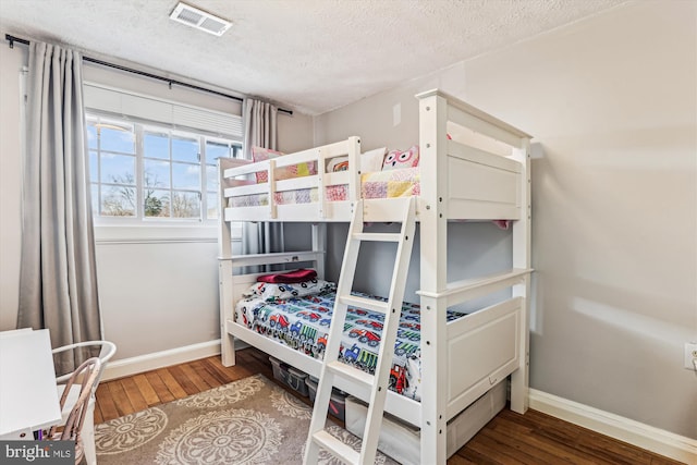 bedroom featuring hardwood / wood-style floors, baseboards, and a textured ceiling