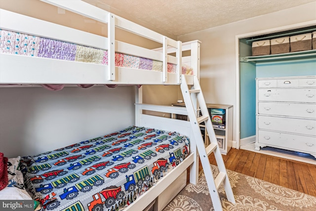 bedroom with a textured ceiling and wood-type flooring