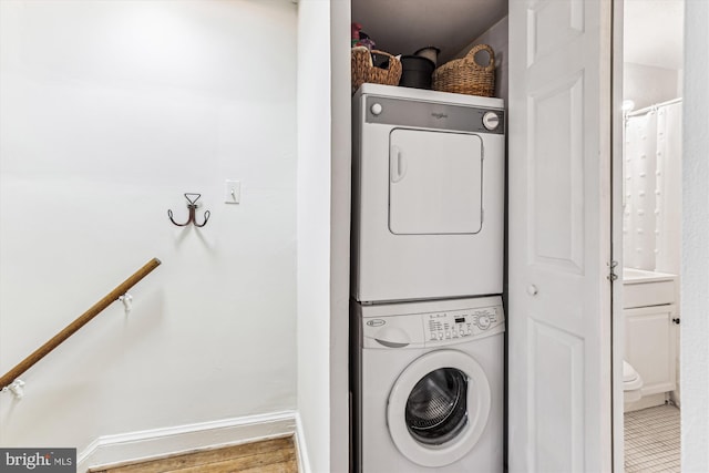 laundry room with laundry area, stacked washer / drying machine, and baseboards