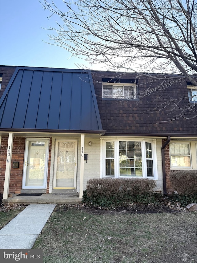 multi unit property featuring brick siding, metal roof, a standing seam roof, and a shingled roof