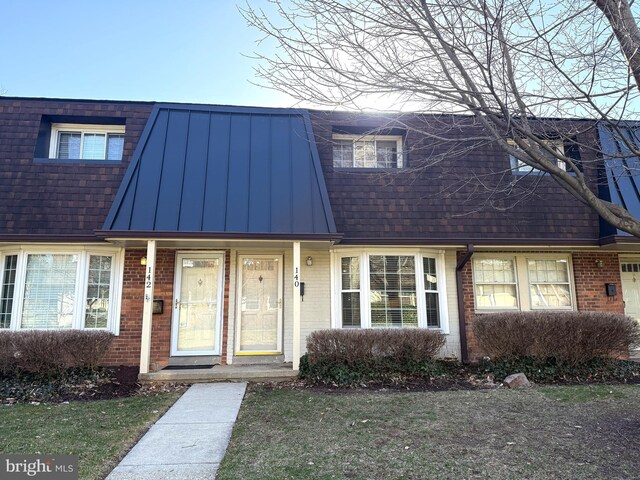 townhome / multi-family property featuring metal roof, brick siding, and a standing seam roof