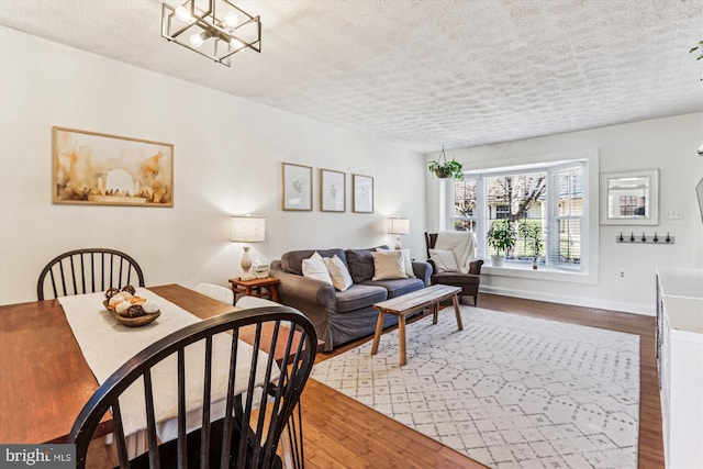 dining area with wood finished floors, baseboards, a chandelier, and a textured ceiling