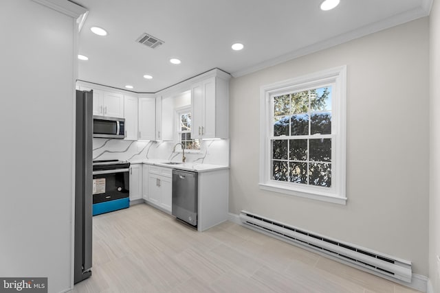 kitchen with sink, baseboard heating, white cabinetry, appliances with stainless steel finishes, and tasteful backsplash