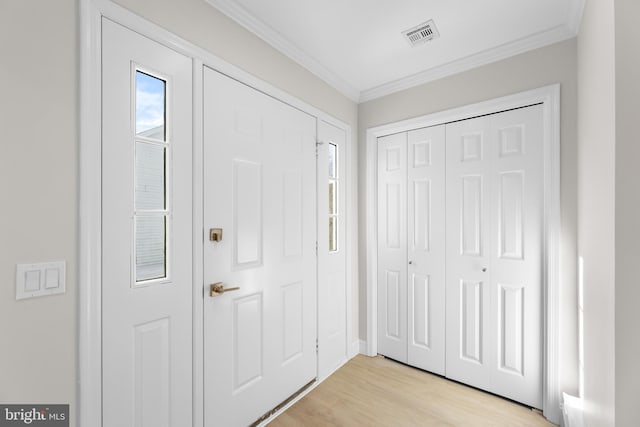 entryway with crown molding and light hardwood / wood-style floors