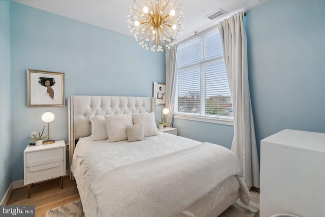 bedroom with a chandelier and hardwood / wood-style floors