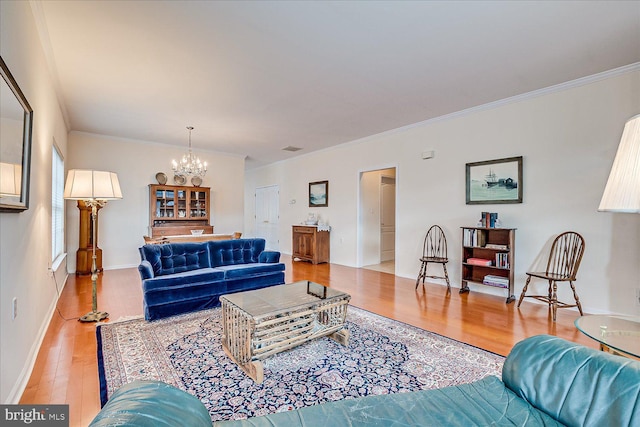 living room featuring ornamental molding, a notable chandelier, and light wood-type flooring