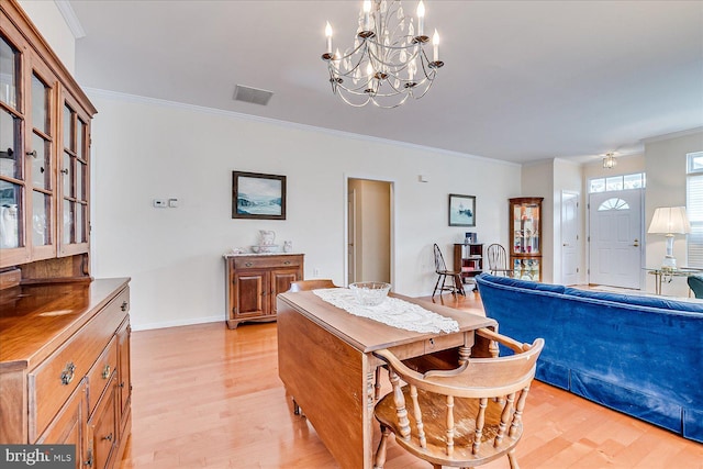 dining area featuring crown molding, a notable chandelier, and light wood-type flooring