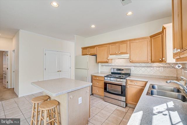 kitchen with a kitchen bar, stainless steel gas range, sink, a center island, and light tile patterned floors