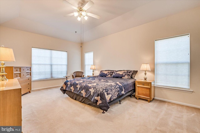 bedroom with light colored carpet, ceiling fan, vaulted ceiling, and multiple windows