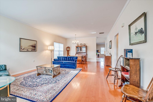 living room featuring hardwood / wood-style floors, crown molding, a wealth of natural light, and a chandelier