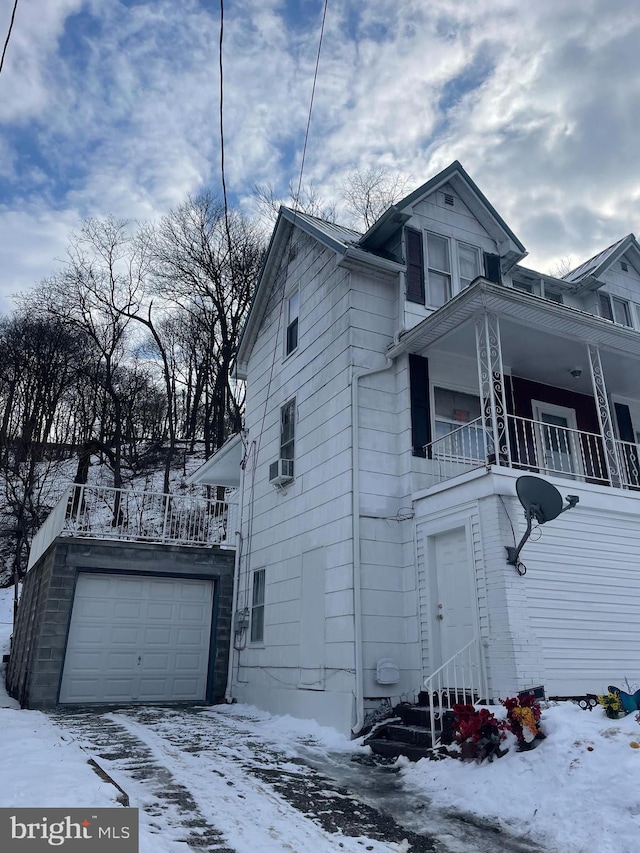 view of snow covered exterior with a garage and a balcony