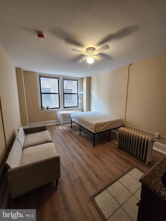 bedroom with hardwood / wood-style flooring, ceiling fan, and radiator