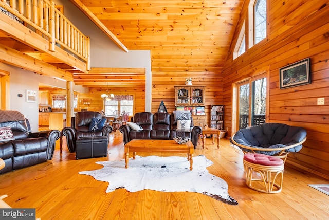 living room with a healthy amount of sunlight, wooden walls, a notable chandelier, and light wood-type flooring