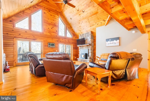 living room featuring wood walls, wood ceiling, high vaulted ceiling, light wood-type flooring, and a fireplace