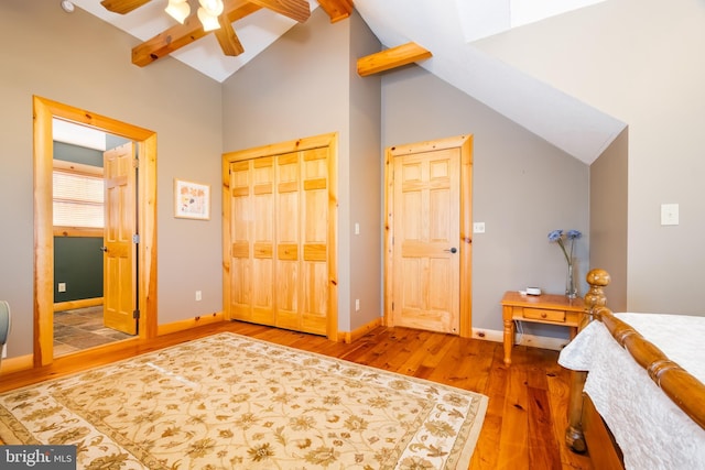 bedroom featuring ceiling fan, wood-type flooring, a closet, and vaulted ceiling with beams