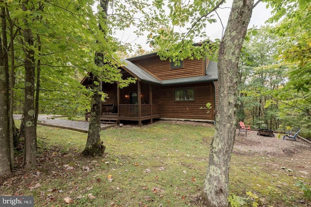 back of property with a yard, a deck, and a fire pit