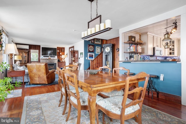 dining space with wood-type flooring and an AC wall unit