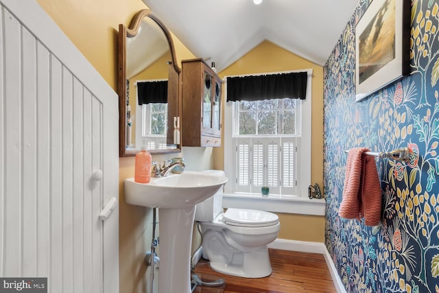 bathroom featuring hardwood / wood-style flooring, lofted ceiling, sink, and toilet