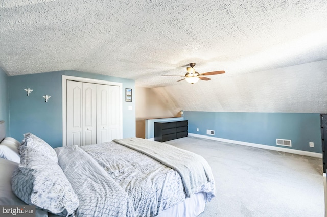 bedroom with vaulted ceiling, carpet floors, ceiling fan, a textured ceiling, and a closet