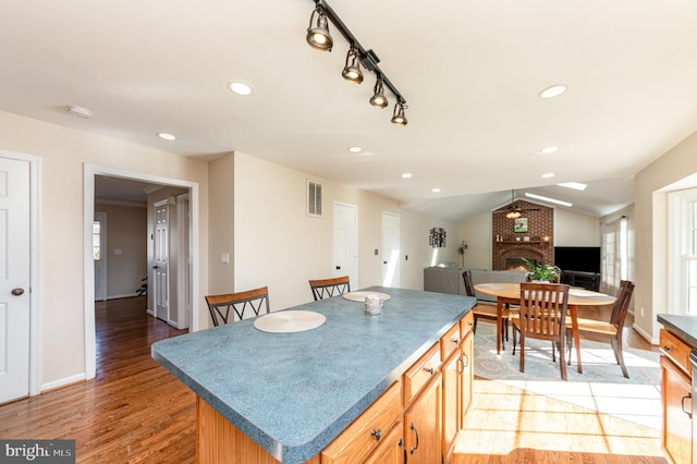 kitchen featuring a center island, a fireplace, visible vents, open floor plan, and vaulted ceiling