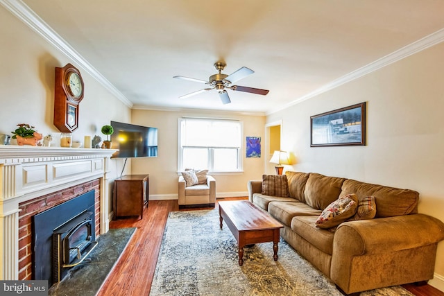 living room featuring hardwood / wood-style flooring, ceiling fan, crown molding, and a tile fireplace