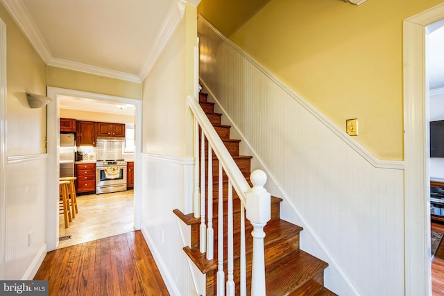 stairway featuring hardwood / wood-style floors and crown molding