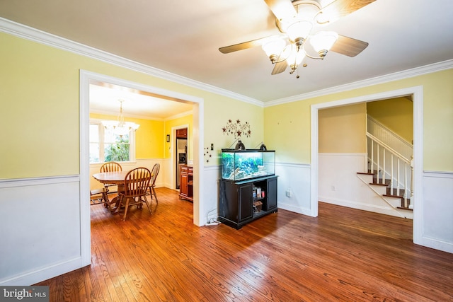 kitchen with dark wood-type flooring, crown molding, and ceiling fan with notable chandelier