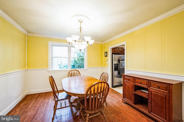 dining room with ornamental molding, hardwood / wood-style floors, and a chandelier