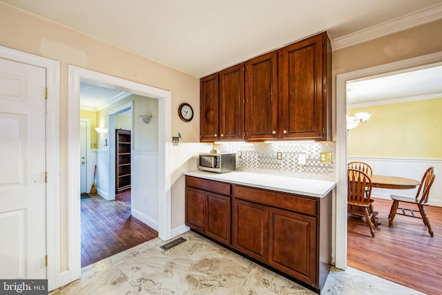 kitchen with a notable chandelier, ornamental molding, light hardwood / wood-style floors, and backsplash