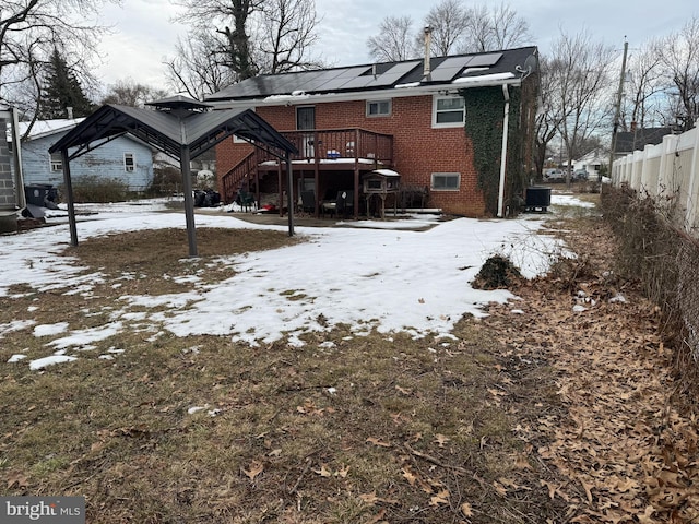 snow covered rear of property featuring a wooden deck and central AC unit