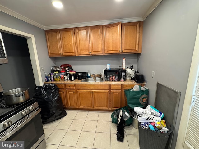 kitchen featuring sink, crown molding, stainless steel gas range oven, and light tile patterned flooring