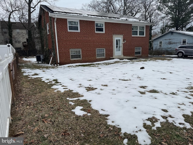 snow covered rear of property with central AC unit