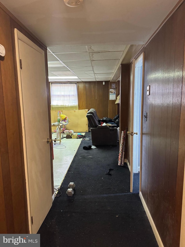 hallway featuring carpet and wood walls