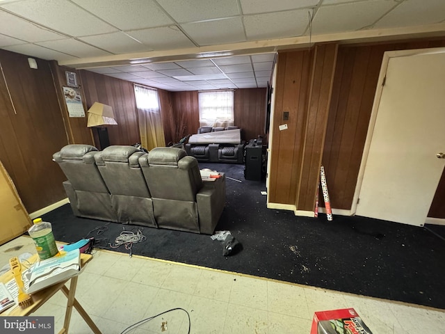 living room with a paneled ceiling and wood walls