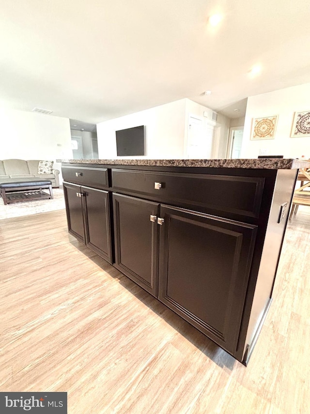 kitchen featuring a center island, dark brown cabinets, and light wood-type flooring