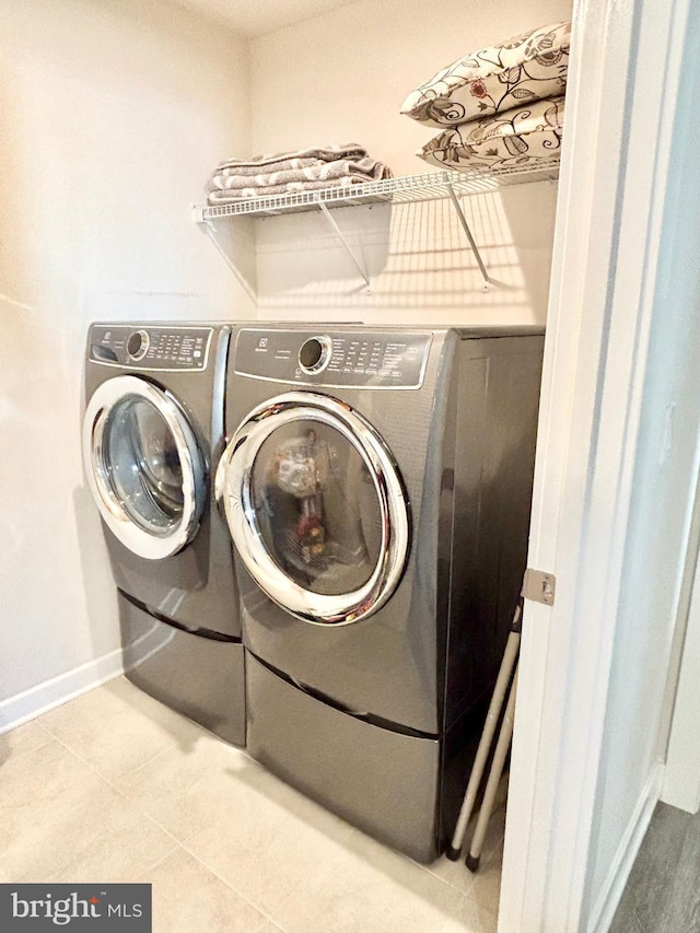 clothes washing area with washer and clothes dryer and light tile patterned floors