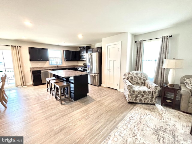 kitchen with sink, stainless steel appliances, a kitchen breakfast bar, a center island, and light wood-type flooring