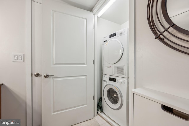 laundry area featuring stacked washer and dryer and light tile patterned floors