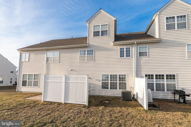 rear view of property featuring cooling unit and a lawn