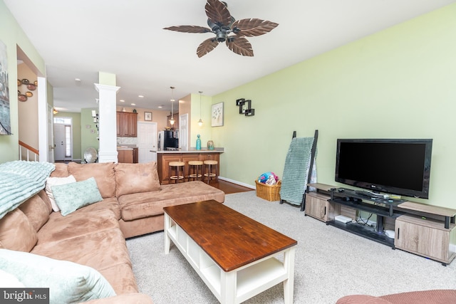 living room featuring decorative columns, light carpet, and ceiling fan