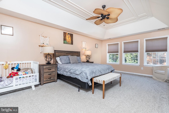 carpeted bedroom with ceiling fan, ornamental molding, and a raised ceiling