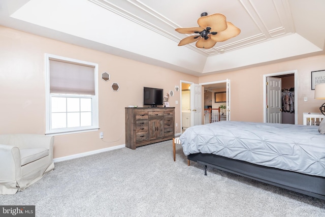 bedroom with a walk in closet, ceiling fan, a raised ceiling, ensuite bath, and a closet