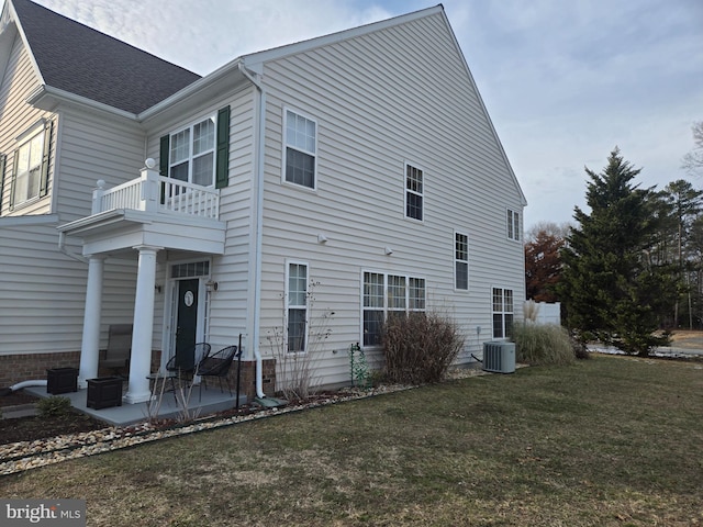 view of side of home featuring a patio, a balcony, a yard, and cooling unit