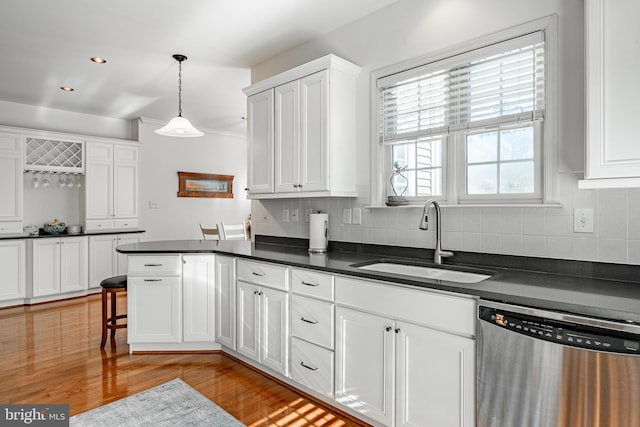 kitchen with sink, light hardwood / wood-style flooring, dishwasher, white cabinets, and decorative light fixtures