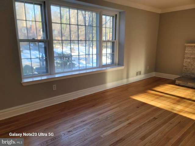 unfurnished living room with hardwood / wood-style flooring, crown molding, and a healthy amount of sunlight